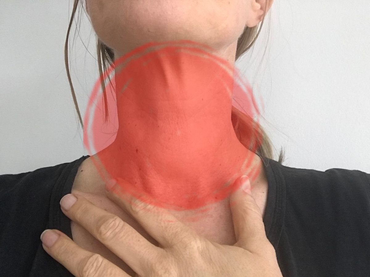 A woman's neck with a red light on the thyroid