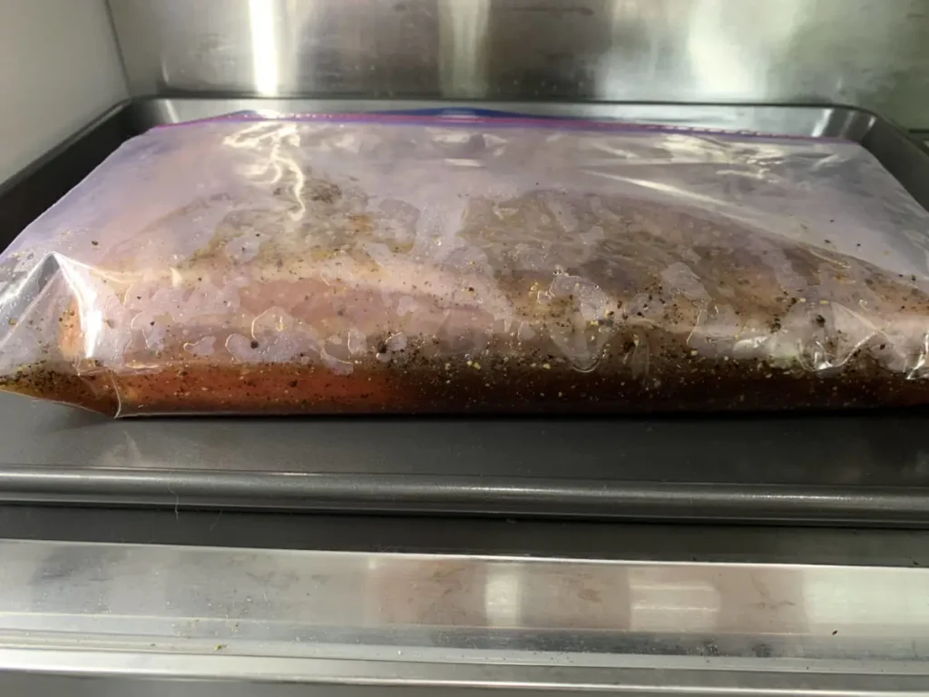 Bacon curing in a sealed bag in the fridge as part of the process for making AIP bacon.