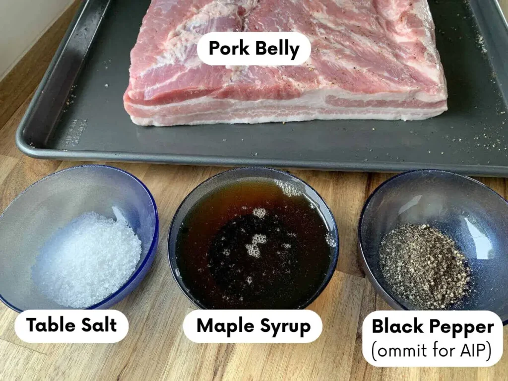 Ingredients for AIP bacon, including salt, maple syrup, and optional black pepper ready for seasoning the pork belly.