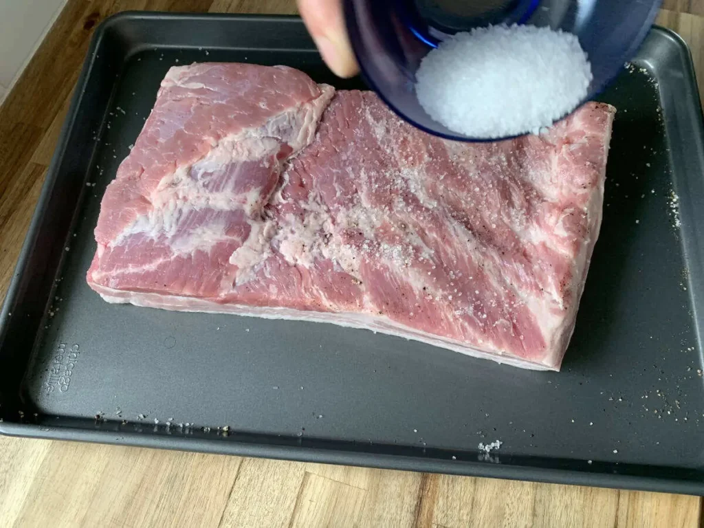 Sprinkling salt on pork belly to begin the curing process for AIP bacon.