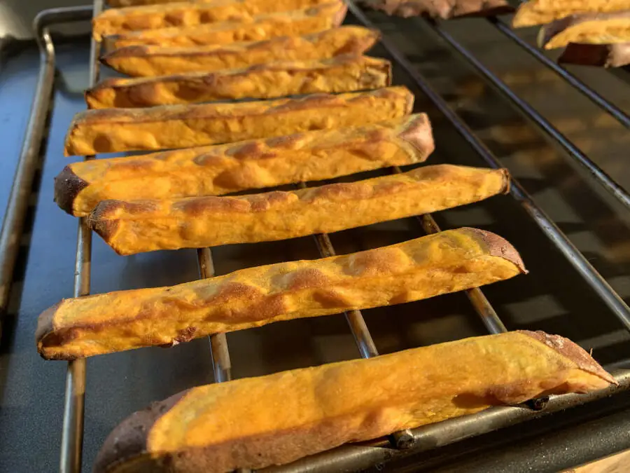 Golden baked sweet potato fries on a grid.