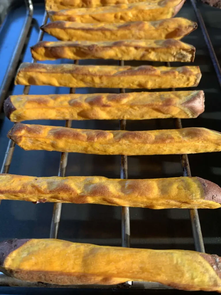 Golden baked sweet potato fries on a grid.