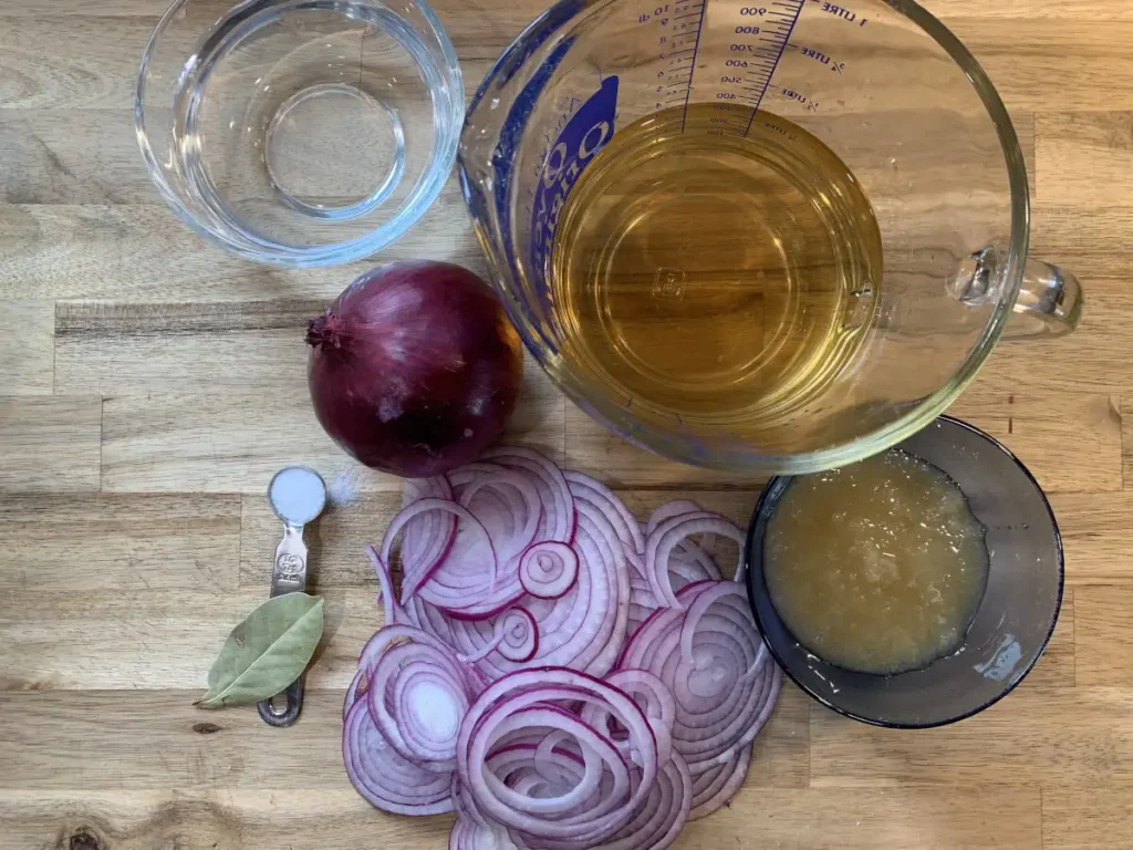 Ingredients for pickled red onions include, red onions, water, apple cider vinegar, honey, salt and a bay leaf.
