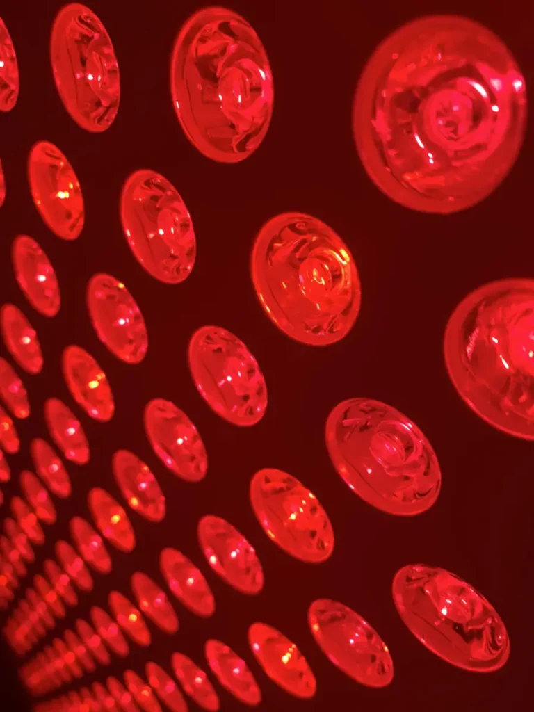 Close-up of glowing red light therapy panel with multiple LED bulbs used for Hashimoto’s support.