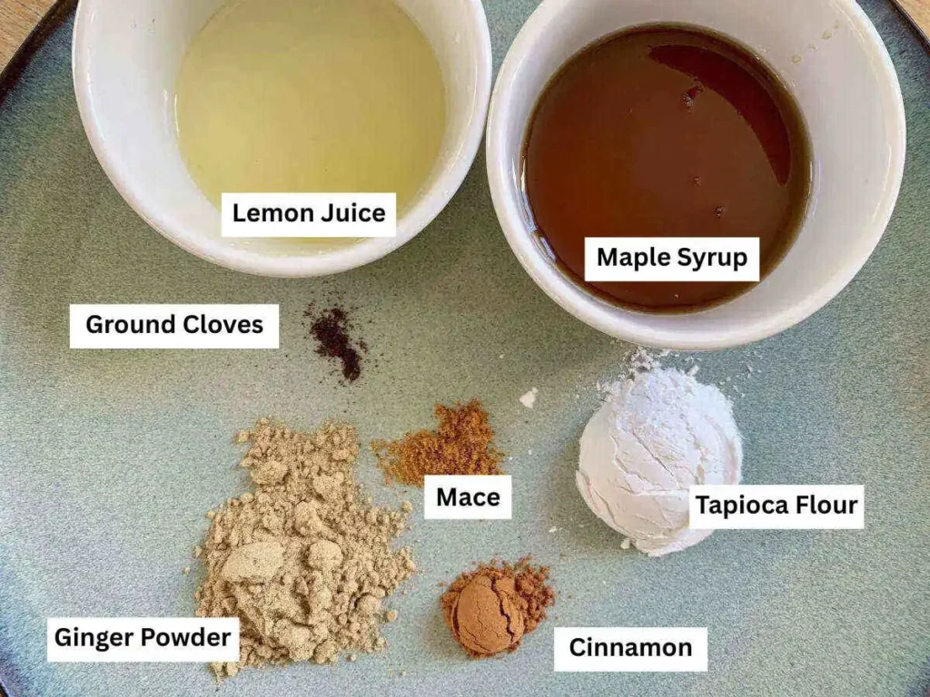 Spices for the AIP apple pie filling. In two white ramekins are Lemon juice and maple syrup. On a blue plate are Tapioca Flour, Ground Cloves, Mace, Ginger Poweder and Cinnamon