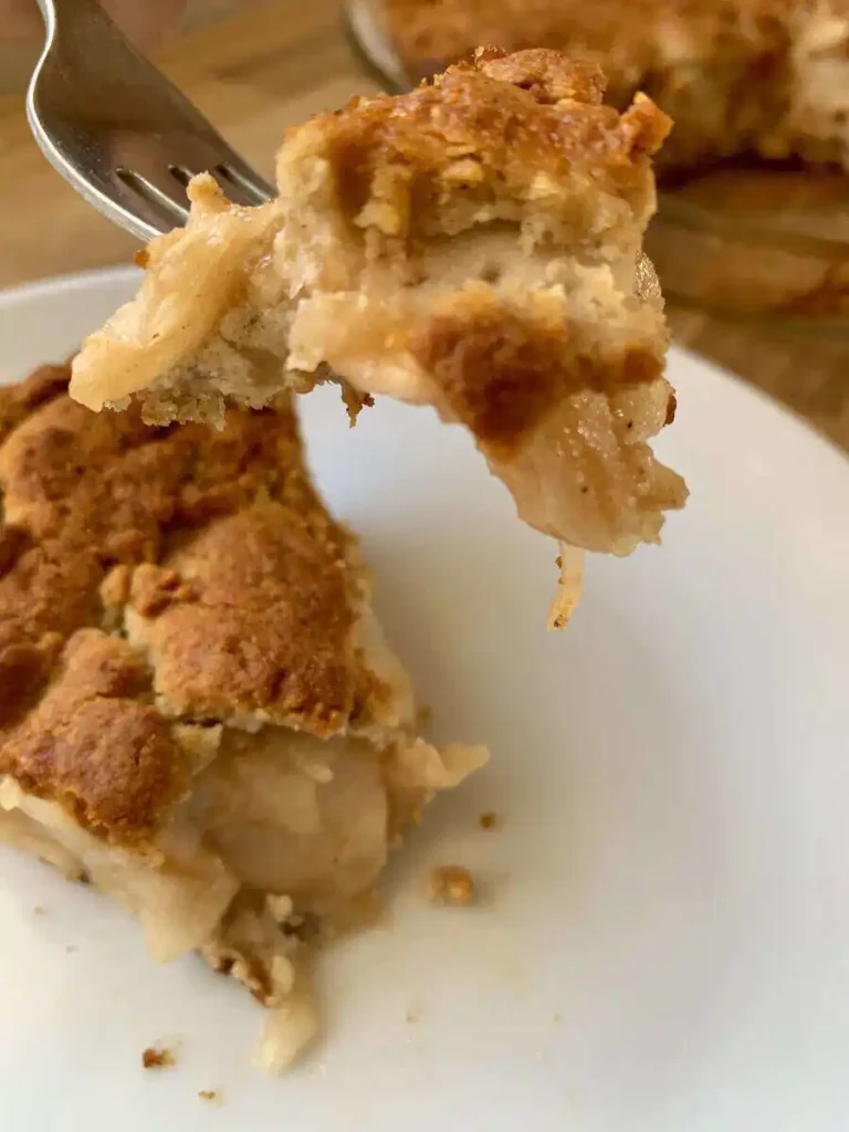 Slice of apple pie with a fork holding a bite of the pie.