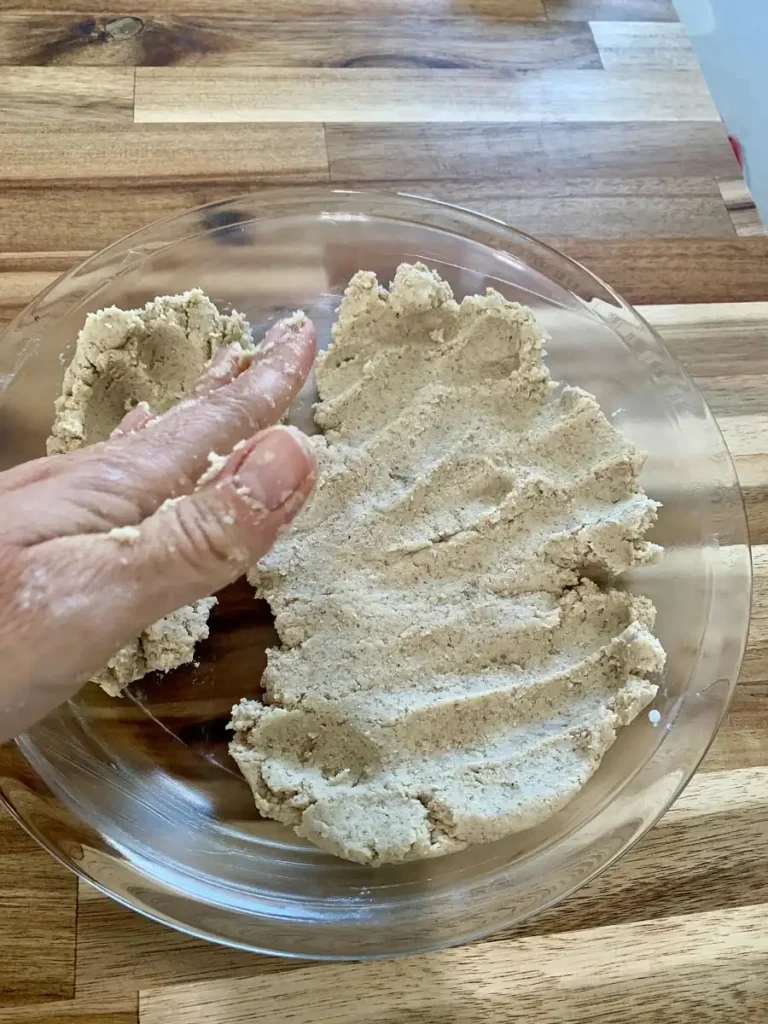 Hand pressing dough into a pie dish to make pie crust.