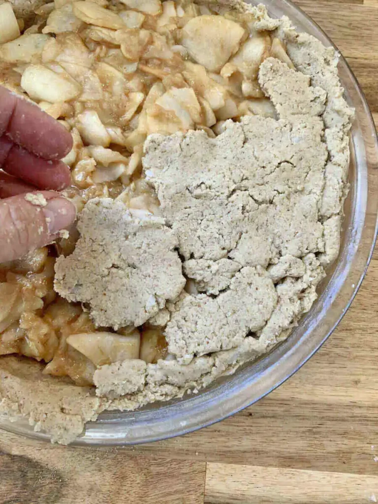 Hand making the top crust of an AIP apple pie.