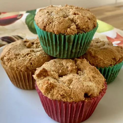 4 AIP apple muffins stacked on a white plate with a dishtowel in the back.
