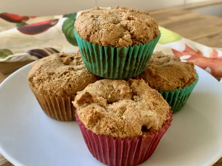 4 AIP apple muffins stacked on a white plate with a dishtowel in the back.