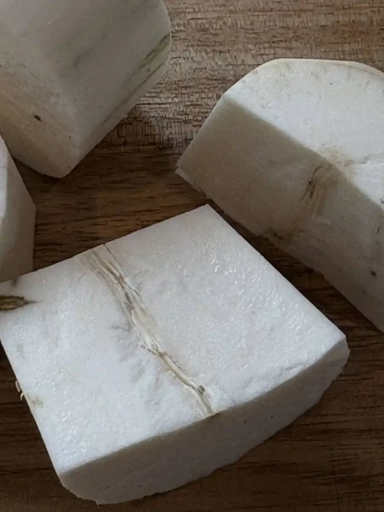 Peeled cassava slices cut in half showing the fibrous centre which has to be removed.