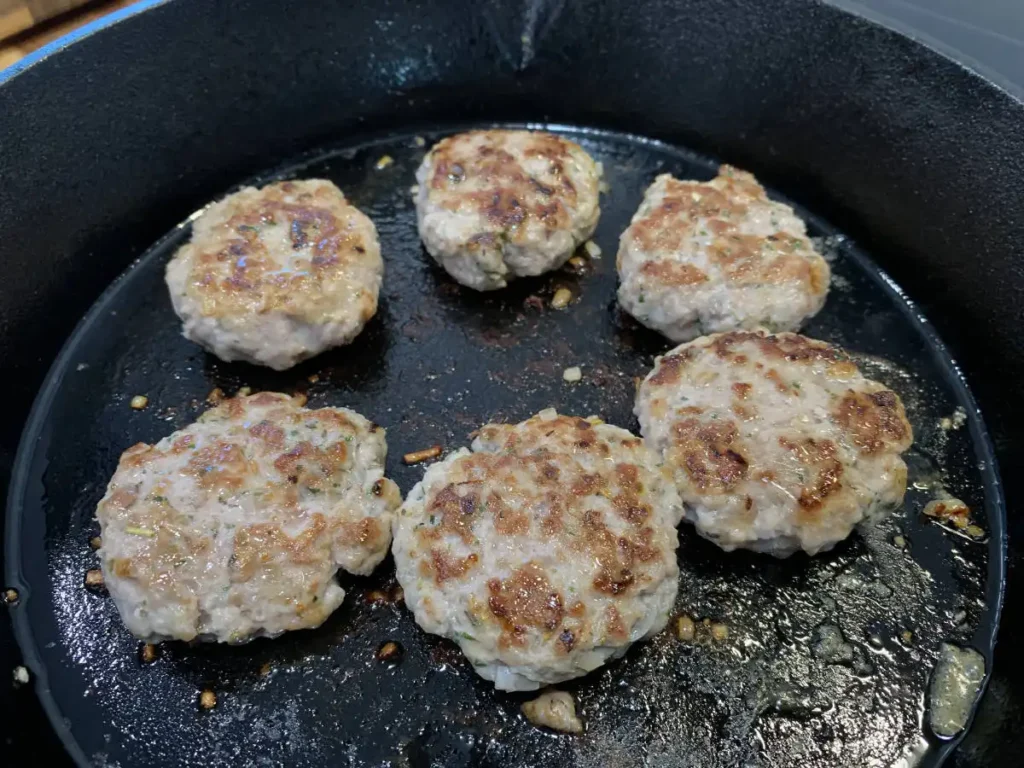 Cooked AIP breakfast sausage patties in a cast iron skillet.