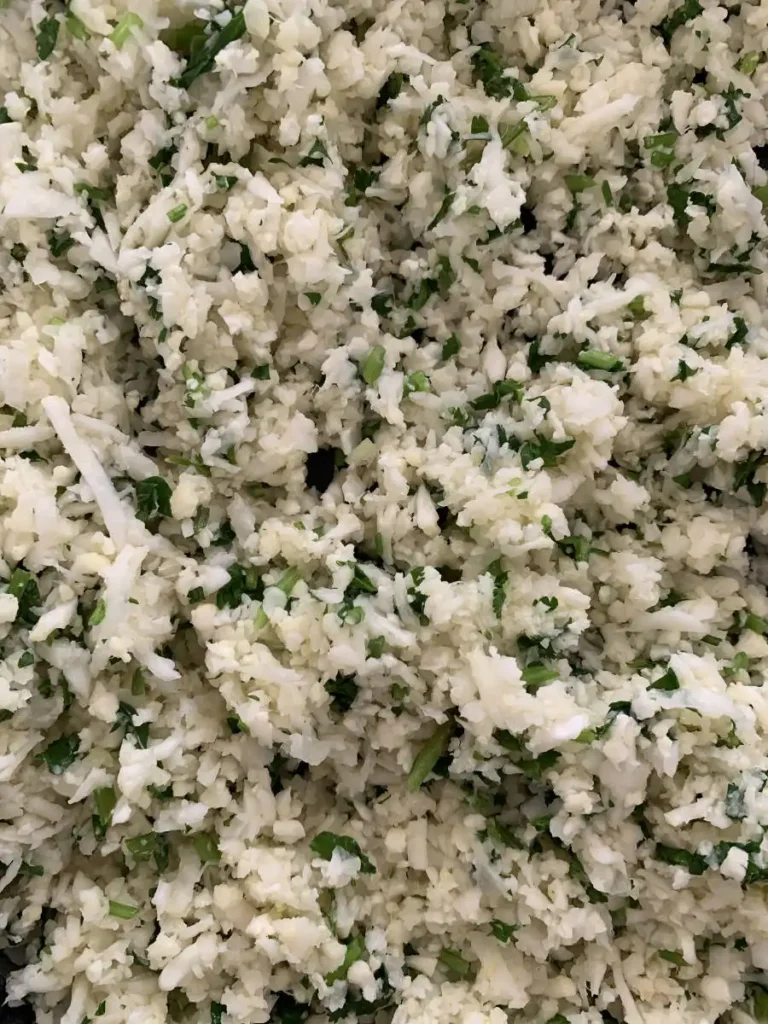 close up of AIP cauliflower rice mixed with some fresh cilantro and lime.